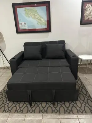 a black couch in a living room with a table at Central Park Apartment in Tamarindo