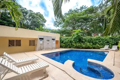 a swimming pool with two lounge chairs and a house at Central Park Apartment in Tamarindo
