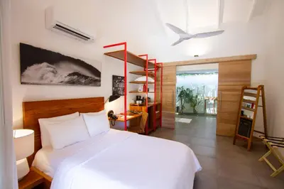a bedroom with a large white bed and a desk at The Gilded Iguana in Nosara