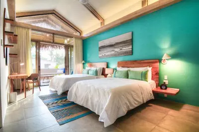 a bedroom with two beds and a blue wall at The Gilded Iguana in Nosara