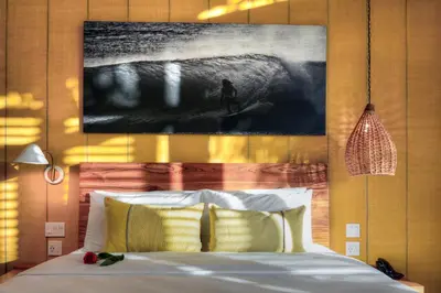 a bedroom with a bed with a painting on the wall at The Gilded Iguana in Nosara