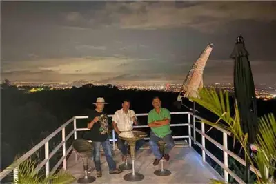 a group of three people standing on a balcony at night at Casa Panorámica con Jacuzzi balcon. Familia Amigos in Robles
