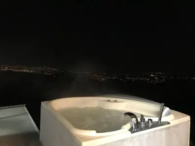 a bath tub with a view of a city at night at Casa Panorámica con Jacuzzi balcon. Familia Amigos in Robles