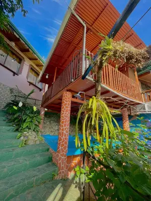 a house with a staircase leading up to a deck at Dreams Lodge Orosi in Cartago