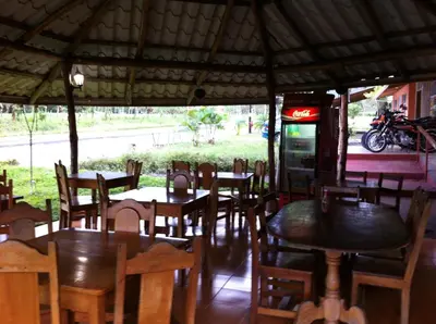 a restaurant with tables and chairs and a soda machine at Hotel Villas Vista Arenal in Fortuna