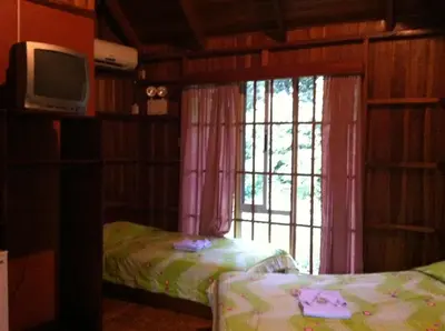 a room with two beds and a television and a window at Hotel Villas Vista Arenal in Fortuna