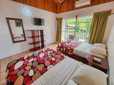 a bedroom with two beds and a mirror and a window at Hotel Sierra Arenal in Fortuna