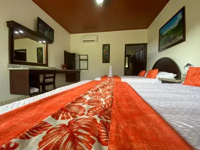 a bedroom with a bed with a red rug on it at Hotel La Pradera del Arenal in Fortuna