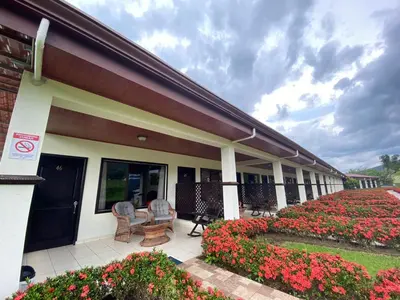 a building with two chairs and flowers on a patio at Hotel La Pradera del Arenal in Fortuna
