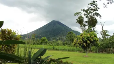 a mountain in the distance with a field and trees at Hotel La Pradera del Arenal in Fortuna
