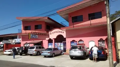 a pink building with cars parked in a parking lot at ECONOMIQUE in Jacó