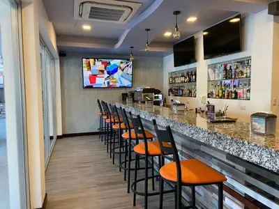 a bar with a row of stools in a restaurant at Hotel Cayuga in Puntarenas