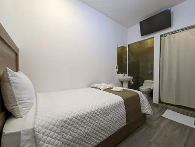 a bedroom with a bed and a bathroom with a shower at Hotel Cayuga in Puntarenas