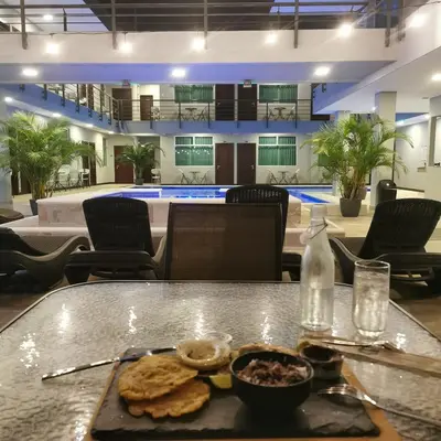 a table with a tray of food on it with a pool at Hotel Cayuga in Puntarenas