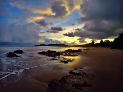 a sunset on a beach with rocks in the water at Hotel Esperanza in Carrillo