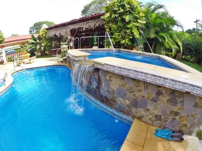 a swimming pool with a stone wall and blue water at Hotel Esperanza in Carrillo