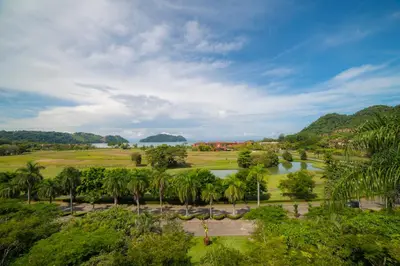 a view of a golf course with a river and palm trees at Vista Bahia 3C 3 bdr Ocean View in Los Suenos in Herradura