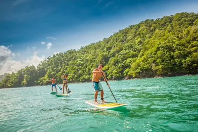 three people are paddle boarding on the water at Vista Bahia 3C 3 bdr Ocean View in Los Suenos in Herradura