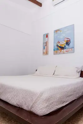 a bedroom with a white bed with two pictures on the wall at Café de Playa Beach Front Hotel in Coco
