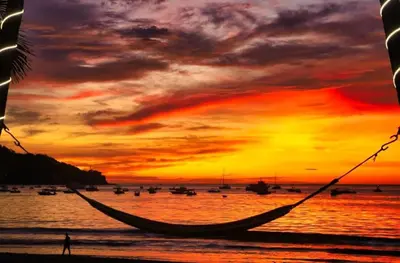 a hammock on the beach with a sunset at Café de Playa Beach Front Hotel in Coco