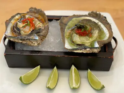 two oysters are on a plate with lime slices at Café de Playa Beach Front Hotel in Coco