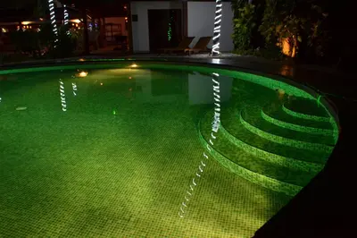 a swimming pool at night with green lights in it at Café de Playa Beach Front Hotel in Coco