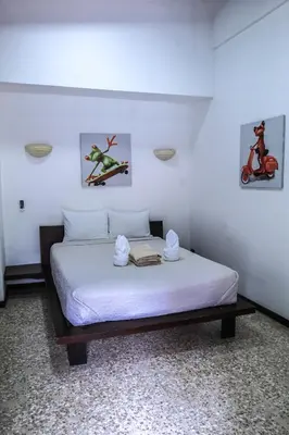 a bedroom with a white bed with two towels on it at Café de Playa Beach Front Hotel in Coco