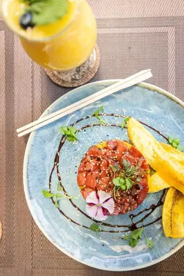 a plate of food with fruit on a table with chopsticks at Paradise Bay Hotel Boutique in Herradura
