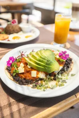 a plate of food with avocado on a table at Paradise Bay Hotel Boutique in Herradura
