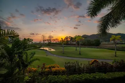 a sunset over a golf course with palm trees at Del Mar 1G 3 bdr Ocean View in Los Suenos in Herradura