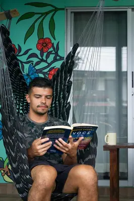 a man sitting in a hammock reading a book at Argdivan Hostel in Fortuna