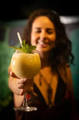 a woman holding a drink with a mint garnishment at Argdivan Hostel in Fortuna