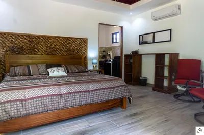 a bedroom with a large bed and a red chair at Hotel Casa Buenavista - Adults only in Sámara