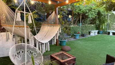 a garden with two hammocks and a green lawn at Airport Traveler's home. in Alajuela City
