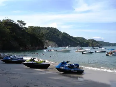 a group of boats on a beach with people in the water at Casa del Sol -Villas Catalinas in Potrero