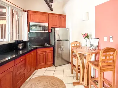 a kitchen with a table and a stainless steel refrigerator at Fenix Hotel - On the Beach in Sámara