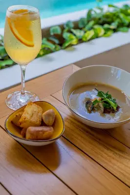 a bowl of soup and a glass of wine on a table at Suitree Experience Hotel in Guanacaste