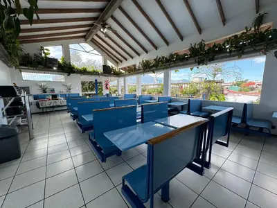 a restaurant with blue chairs and tables and windows at Hotel Cacts in San José
