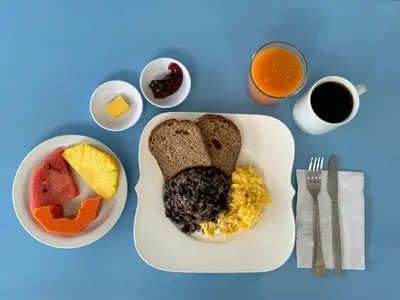 a plate of breakfast food with toast eggs fruit and juice at Hotel Cacts in San José
