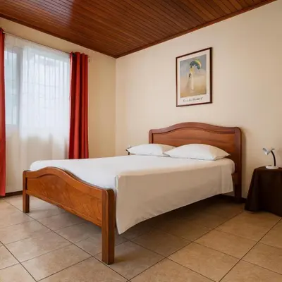 a bedroom with a bed and a red curtain at Casa Cafetal Aeropuerto in Alajuela City