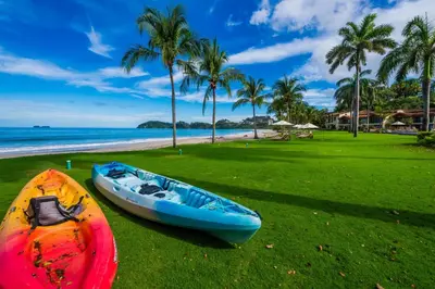 two boats sitting on the grass near the beach at Palms 23 Luxury Beachfront Villa in Playa Flamingo