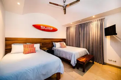 a hotel room with two beds and a surfboard on the wall at A Tamarindo Sunset in Tamarindo