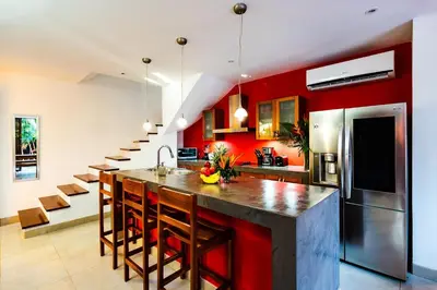 a kitchen with red walls and a kitchen island with chairs at A Tamarindo Sunset in Tamarindo