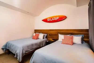two beds in a room with a surf sign on the wall at A Tamarindo Sunset in Tamarindo