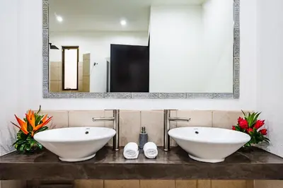 a bathroom with two white sinks and a mirror at A Tamarindo Sunset in Tamarindo