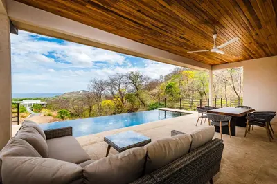 a living room with a couch and a swimming pool at Casa Serena - Ocean View 3 Br House in Brasilito