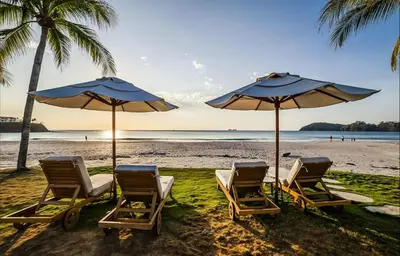 a group of chairs and umbrellas on a beach at Palms 26 Sueños Del Sol in Playa Flamingo