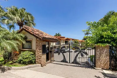 a gate to a house with palm trees at Palms 26 Sueños Del Sol in Playa Flamingo