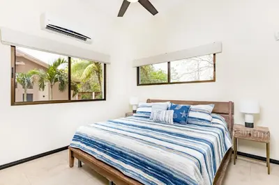 a bedroom with a bed and two windows at Flamingo Estates 18- 4 Br House With Pool in Brasilito