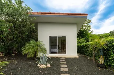 a small white house with palm trees and bushes at The Haven-Mar Vista 2 Br House With Pool And 1 Br Casita in Brasilito